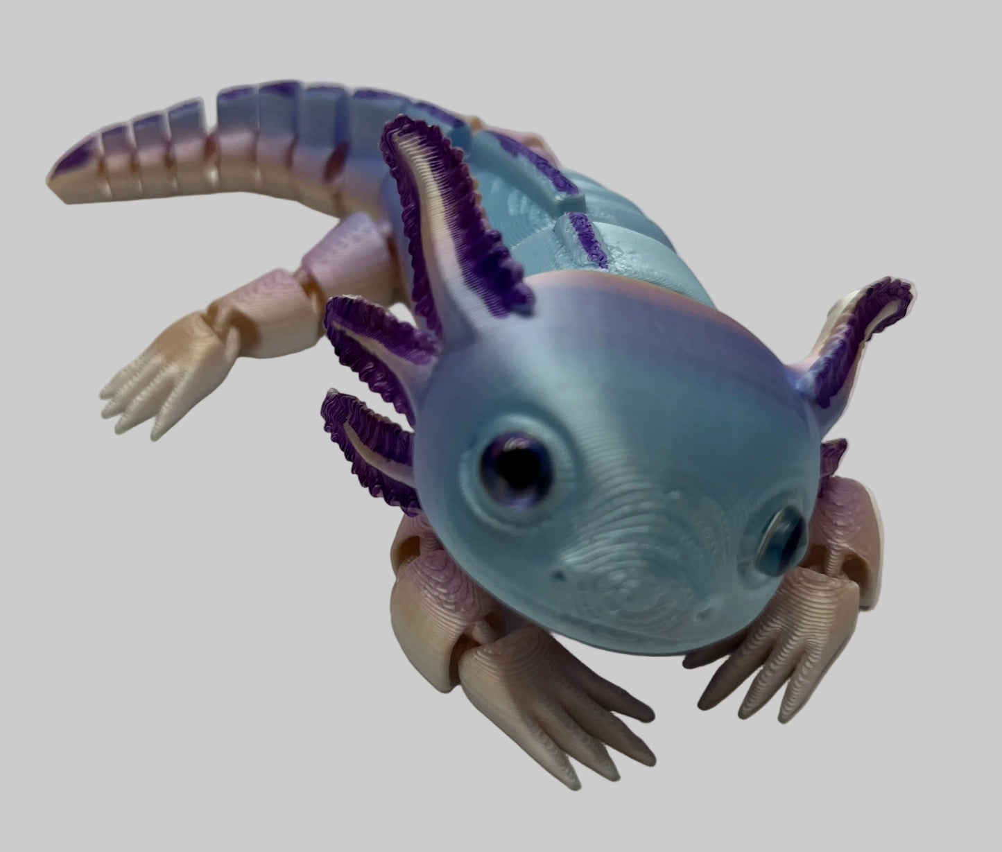 Toy figure of an Axolotl with a light blue body and purple accents on a white background