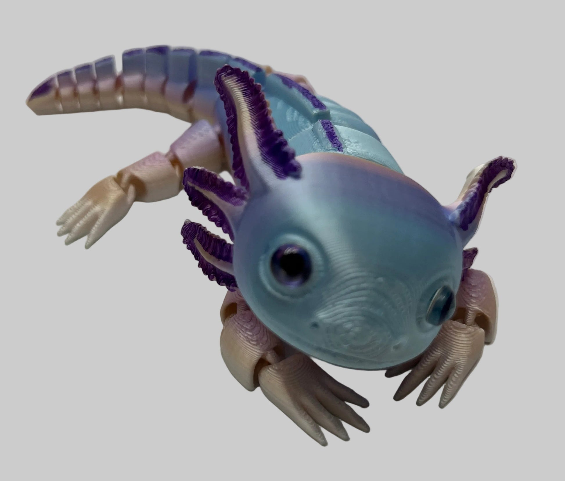 Toy figure of an Axolotl with a light blue body and purple accents on a white background
