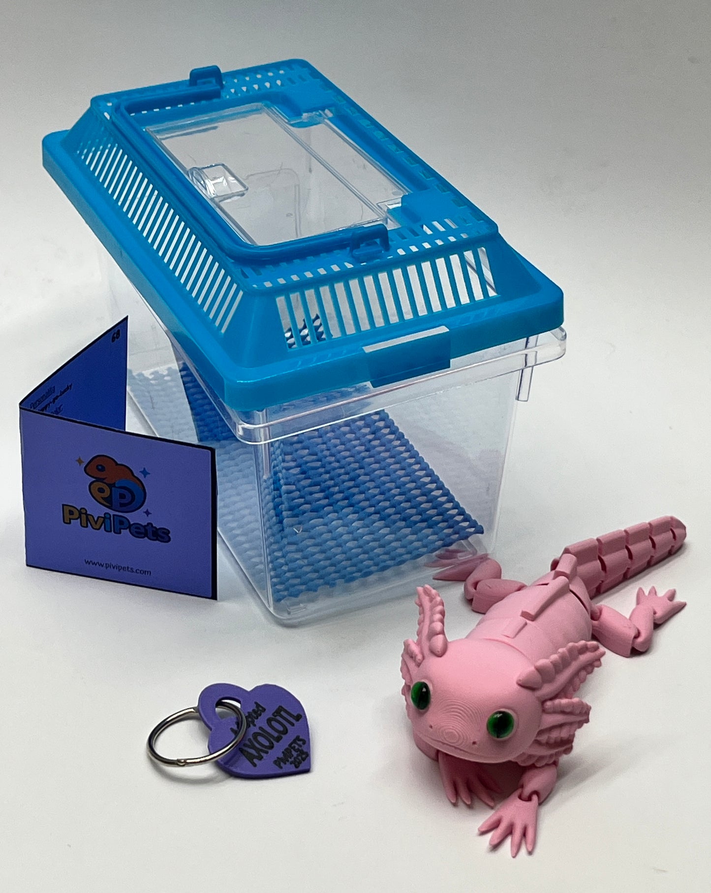 Blue and clear plastic terrarium with a pink axolotl toy and a purple keychain on a white background.